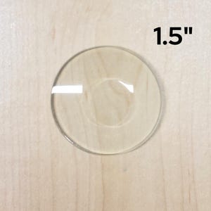 May include: A clear glass circle, 1.5 inches in diameter, with a slightly raised center.