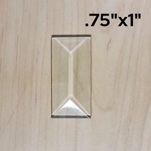 May include: A clear glass tile with beveled edges, measuring 0.75 inches by 1 inch.