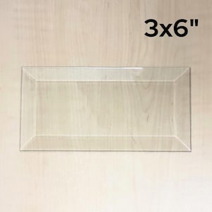 May include: A clear glass tray with beveled edges. The tray is 3 inches by 6 inches.