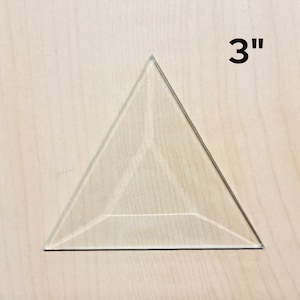 May include: A clear glass triangle with beveled edges, measuring 3 inches across.