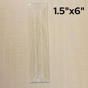 May include: A clear glass tile with beveled edges, measuring 1.5 inches by 6 inches.