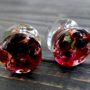 May include: Pair of clear glass ear gauges with red and gold accents. The gauges are filled with red and gold flakes and have a floral design.