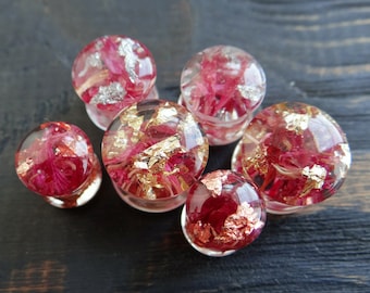 May include: Six round, clear resin ear gauges with pink and red flower petals and gold or silver flakes inside.