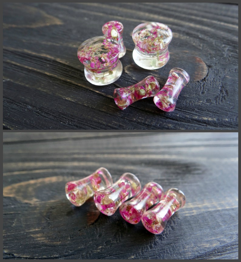 May include: A set of six clear acrylic ear gauges with pink and gold flower accents. The gauges are in various sizes and shapes, including round, cylindrical, and flared.