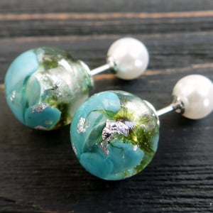May include: A pair of silver earrings with a pearl on one end and a blue and green resin sphere on the other end. The resin sphere contains silver flakes and small blue and green pieces.