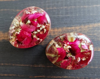 May include: Two round resin earrings with pink flower petals and gold flakes embedded inside.