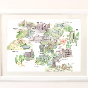 May include: A framed watercolour map print featuring illustrations of various locations, including castles, churches, and bridges. The artwork is framed in a white border. The map features green, blue, and brown hues.
