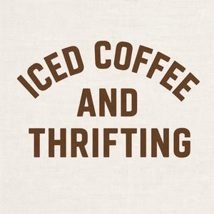 Op de afbeelding: Een lichtbeige stoffen achtergrond met donkerbruine tekst in een vetgedrukt, schreefloos lettertype. De tekst is gerangschikt in drie regels, met de woorden ICED COFFEE bovenaan in een boog, gevolgd door het woord AND en THRIFTING onderaan.