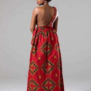 May include: A red maxi dress with a one-shoulder design and a geometric pattern. The dress is made of a lightweight fabric and has a flowing silhouette.