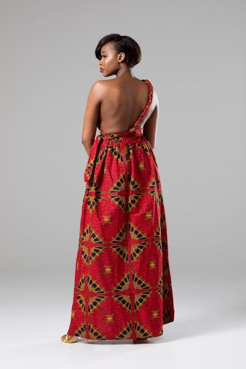 May include: A red maxi dress with a one-shoulder design and a geometric pattern. The dress is made of a lightweight fabric and has a flowing silhouette.