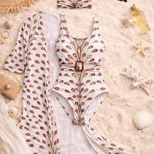 May include: A white swimsuit, matching kimono, and headband set with a brown and orange feather-like pattern. The swimsuit has a brown buckle. Accessories include sunglasses, a straw hat, and seashells.