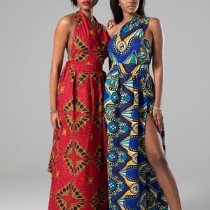 May include: Two women wearing long, colorful maxi dresses with geometric patterns. The dress on the left is red with gold accents, while the dress on the right is blue with yellow and green accents. Both dresses have a halter neckline and a side slit.