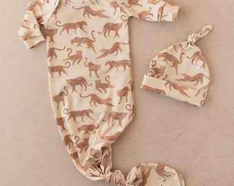 Könnte beinhalten: Ein beiger Baby-Strampler und eine passende Mütze mit braunem Leopardenmuster.