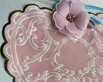 May include: A pink heart-shaped card with a white filigree design and a pink flower with a sparkly center.