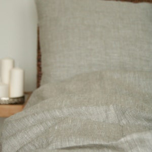 May include: A white ceramic mug with a black handle and the text "But First, Coffee" in a black, handwritten-style font. The mug is sitting on a white surface.