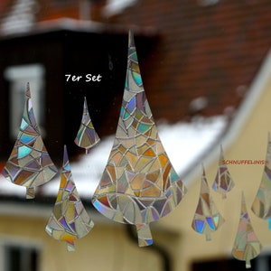 Könnte beinhalten: Ein Set mit sieben schimmernden, glasmalereiartigen Weihnachtsbaum-Fensteraufklebern. Die Bäume sind in verschiedenen Größen und mit einem geometrischen Muster versehen. Der Text "7er Set" ist auf dem Bild zu sehen.