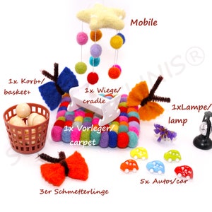 Könnte beinhalten: Eine Sammlung handgefertigter Kinderzimmerdekorationen. Enthält ein Filz-Mobile mit bunten Kugeln und einem Stern, eine kleine weiße Wiege, einen bunten Filzteppich, Filzschmetterlinge, einen Korb mit Kugeln und Spielzeugautos.