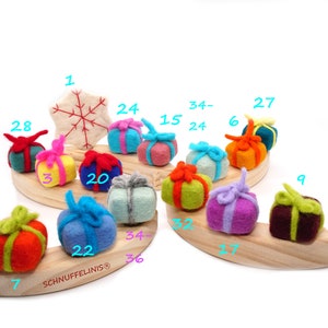 May include: A wooden advent calendar with felt ornaments shaped like wrapped gifts. The gifts are in various colors, including red, green, blue, yellow, purple, and brown. The numbers 1 through 36 are written on the ornaments.