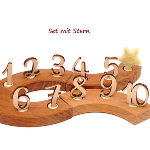 Op de afbeelding: Houten cijferset met een ster, met de cijfers 1 tot en met 10. Elk lichtbruin cijfer staat op een houten basis. De tekst "Set mit Stern" is in de afbeelding te zien.