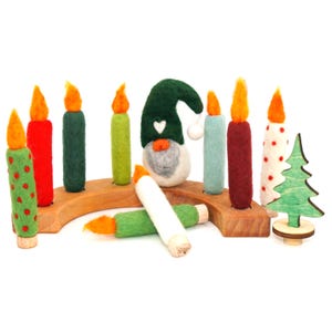 May include: A wooden arched candle holder base featuring multiple felted wool candles in various colors including red, green, and white with orange flames. A felted gnome with a green hat and a small green wooden tree are included in the set.