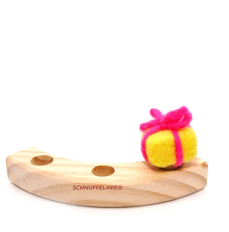 May include: A yellow felt gift box with a pink felt ribbon sits on a wooden base with the text "SCHNUFFELINIS&reg;" printed on it.