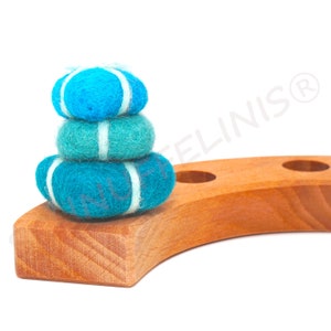 Op de afbeelding: Een stapel van drie blauwe en witte viltballen op een houten standaard. De ballen zijn gerangschikt in een piramidevorm.