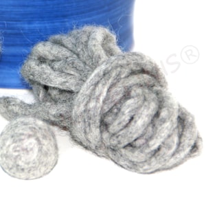 May include: Close-up of gray wool roving and a small wool ball. The roving is tightly coiled, and the ball is round. A blue spool is visible in the background. This image is ideal for craft projects.