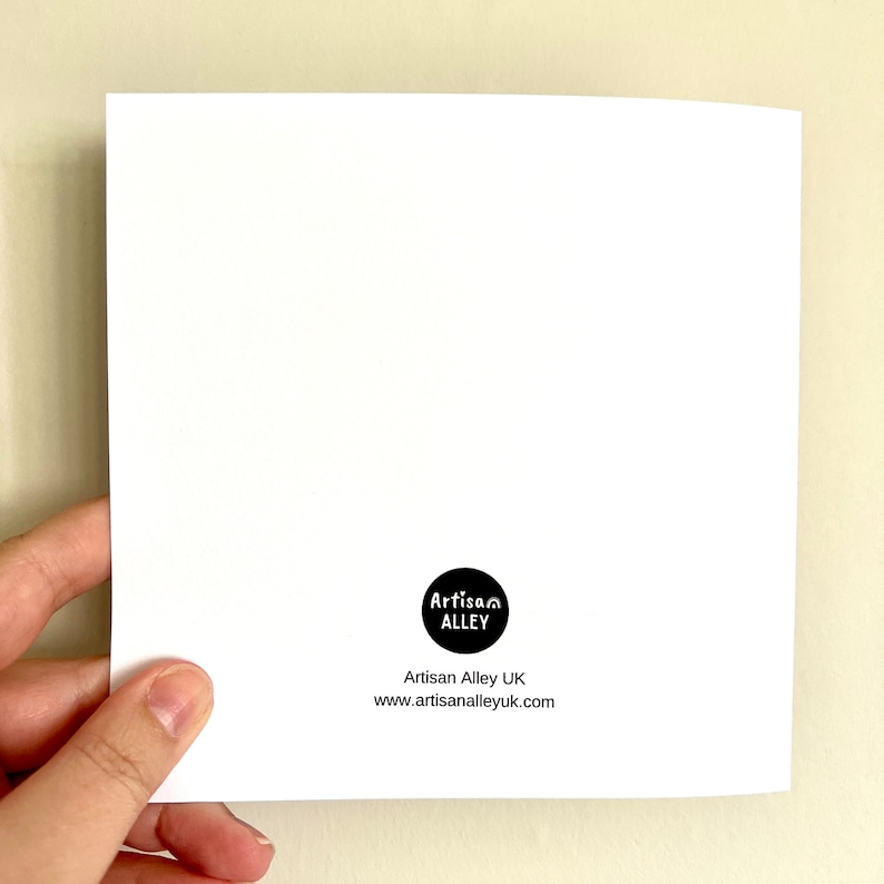 May include: A white card held in a hand, with a black circular logo reading "Artisan Alley". Below the logo is "Artisan Alley UK" and the website address www.artisanalleyuk.com.