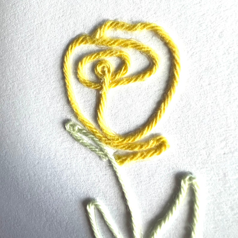 Peut inclure: Une fleur brod&eacute;e jaune avec une tige et des feuilles vertes. La fleur est r&eacute;alis&eacute;e avec un seul brin de fil et est brod&eacute;e en forme circulaire.
