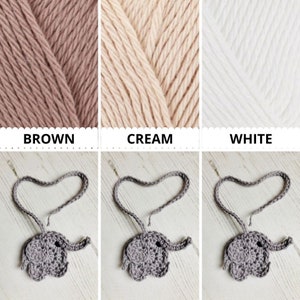 Peut inclure: Trois breloques &eacute;l&eacute;phant en crochet gris, chacune avec une boucle de fil en forme de c&oelig;ur. Le fil est pr&eacute;sent&eacute; en trois couleurs&nbsp;: marron, cr&egrave;me et blanc.