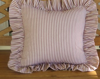 May include: A white and burgundy striped cushion with a ruffled edge. The cushion is sitting on a wooden bench.