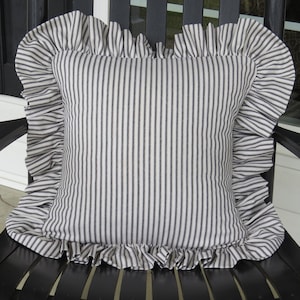 May include: A black and white striped pillow with a ruffled edge. The pillow is made of a soft, cotton fabric and is perfect for adding a touch of farmhouse style to any room.