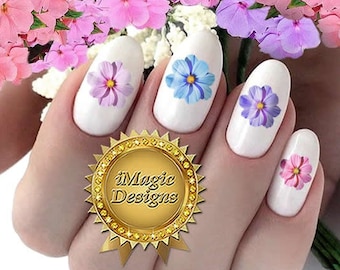 Op de afbeelding: Close-up van een hand met vijf vingernagels versierd met kleurrijke bloem nagelkunst stickers. De stickers bevatten blauwe, roze en paarse bloemen.