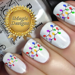 May include: White nail polish with colorful Christmas lights nail art design. The nail art design features a string of lights with red, yellow, green, blue, and purple bulbs.