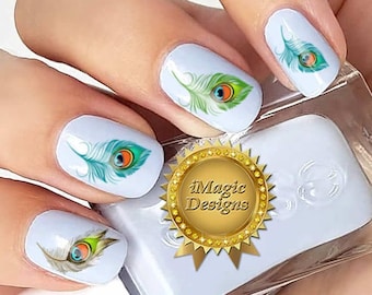 Op de afbeelding: Nageldecoraties met pauwenveren met een blauw, groen en oranje oogontwerp. De stickers zijn aangebracht op lichtblauwe nagellak.