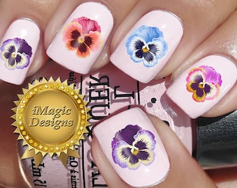Op de afbeelding: Vijf vingernagels met verschillende nagelkunst met een ontwerp van een viooltje. De nagelkunst is in tinten van paars, blauw, roze en geel.