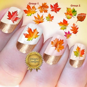 May include: Nail art featuring autumn-themed maple leaf designs. The nails have a gold glitter French tip and a white or light pink base. The maple leaves are in shades of red, orange, and yellow. The image also includes the text "iMagic Designs".