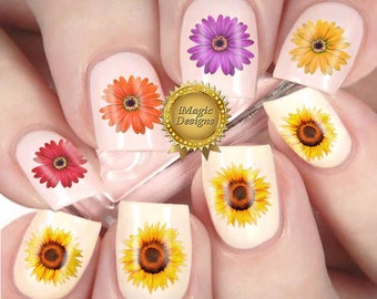 Op de afbeelding: Nageldecoraties met verschillende bloemmotieven, waaronder zonnebloemen, madeliefjes en gerbera's. De decoraties zijn te zien op een set nagels.