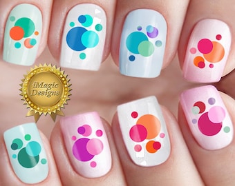 Op de afbeelding: Tien vingernagels met verschillende kleurrijke cirkelontwerpen. Elke nagel heeft een ander kleurenschema van cirkels, waaronder roze, blauw, groen, oranje en rood.