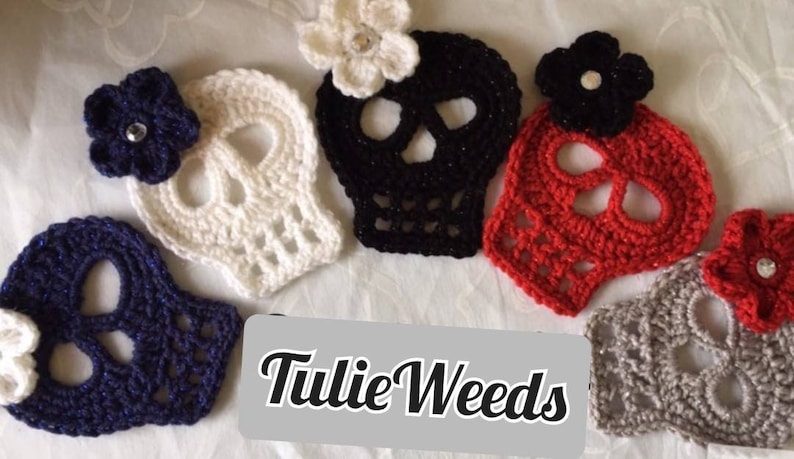 May include: Five crocheted skull ornaments with flowers. The skulls are white, black, red, gray, and navy blue. The flowers are white, black, and red. The text "Tulie Weeds" is visible in the image.