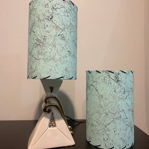 Op de afbeelding: Twee vintage lampen met witte keramische bases en groene en witte gepatroneerde lampenkappen. De lampenkappen hebben een zwarte gestikte rand.