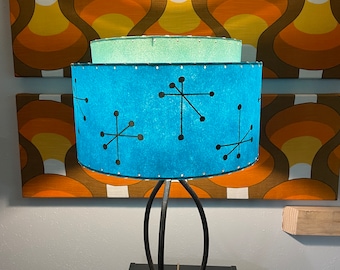 May include: A blue and black mid-century modern table lamp with a geometric pattern on the shade. The lamp is on a black table.