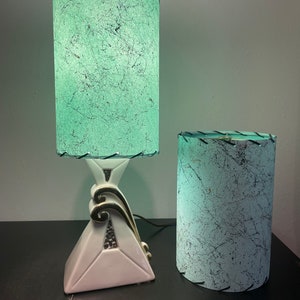 Op de afbeelding: Twee vintage lampen met groene en witte gepatroneerde lampenkappen. De grotere lamp heeft een witte keramische voet met gouden accenten. De kleinere lamp heeft een witte keramische voet.