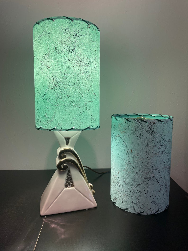 Op de afbeelding: Twee vintage lampen met groene en witte gepatroneerde lampenkappen. De grotere lamp heeft een witte keramische voet met gouden accenten. De kleinere lamp heeft een witte keramische voet.