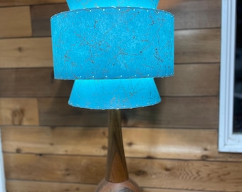 May include: A mid-century modern table lamp with a wooden base and a three-tiered blue lampshade.