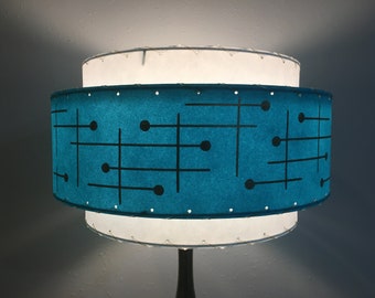 May include: A two-tiered lampshade with a white top and a teal bottom. The teal bottom has a geometric pattern of black lines and circles.