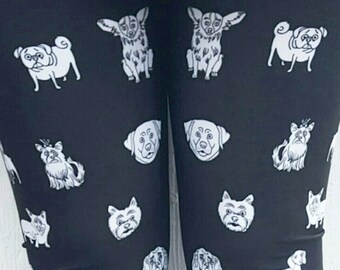 May include: Black leggings with a white print of various dog breeds. The leggings are worn by a person wearing black shoes.