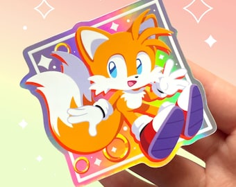 Könnte beinhalten: Ein holografischer Aufkleber mit einem Comic-Fuchs-Charakter mit einem großen, buschigen Schwanz. Der Fuchs trägt rote Schuhe und winkt mit einer Hand. Der Aufkleber hat einen regenbogenfarbenen, schillernden Hintergrund mit weißen Sternen und goldenen Ringen.