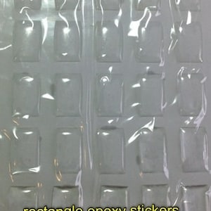 May include: Clear rectangle epoxy stickers, approximately 0.63 inches by 0.43 inches, are arranged in a grid pattern. The stickers are packaged in a clear plastic sheet. The text "rectangle epoxy stickers approx. 16mm x 11mm" is visible.