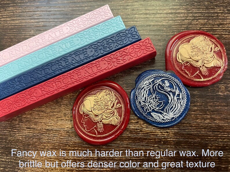 May include: Four sticks of sealing wax in pink, blue, navy blue, and red with the word "RNDCREATE" embossed on each stick. Three wax seals are shown, one with a gold design on a red background, one with a silver design on a blue background, and one with a gold design on a red background.